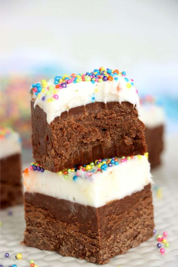 Closeup shot of two frosted fudge squares stacked atop one another with bite taken out of top piece