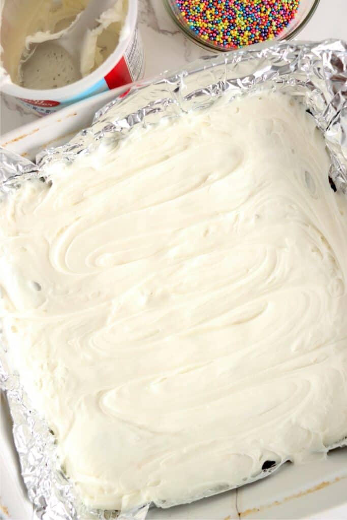 Overhead shot of frosted fudge in baking dish lined with foil