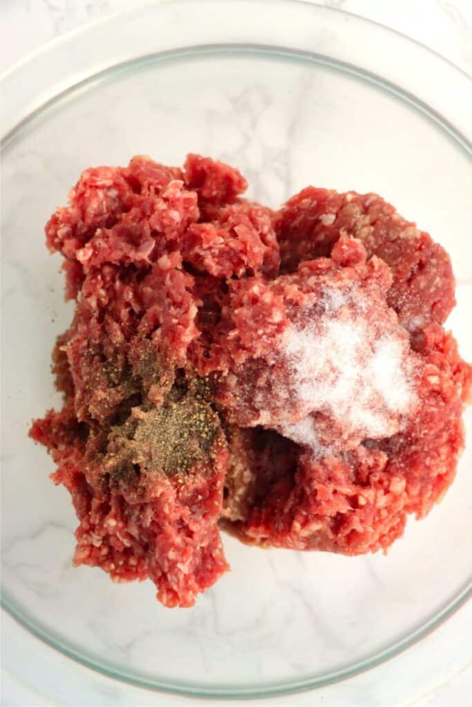 Overehead shot of ground beef, salt, and pepper in mixing bowl