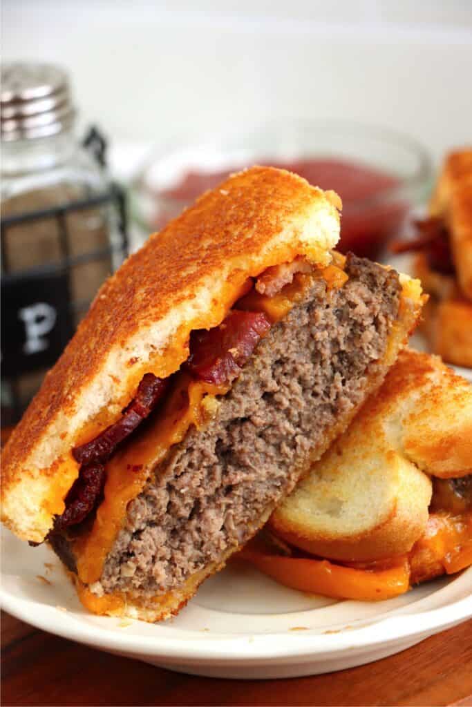  Closeup shot of two halves of grilled cheese bacon hamburger on plate