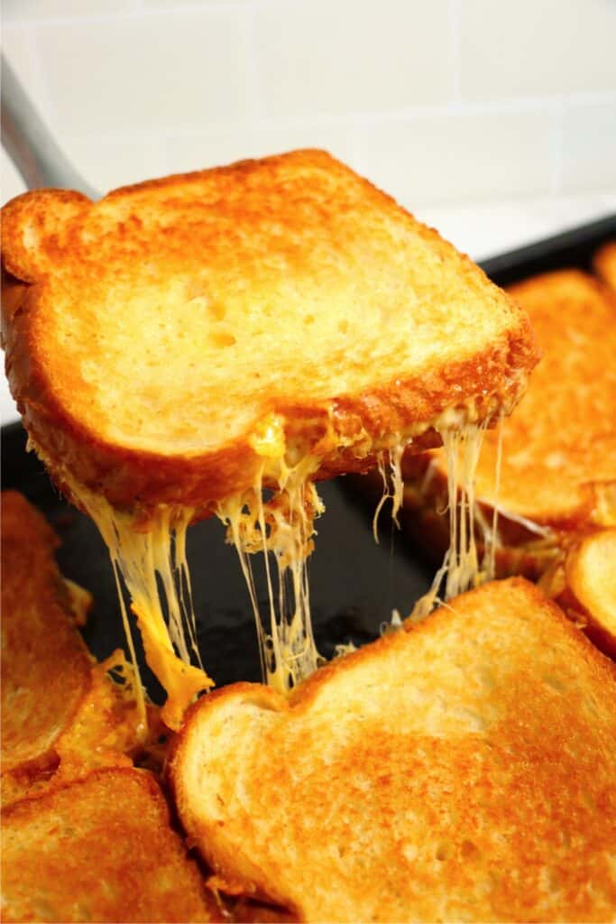 Closeup shot of grilled cheese sandwich being removed from baking sheet with spatula