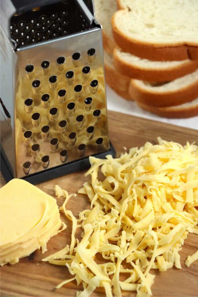 Closeup shot of shredded cheese and cheese grater on cutting board