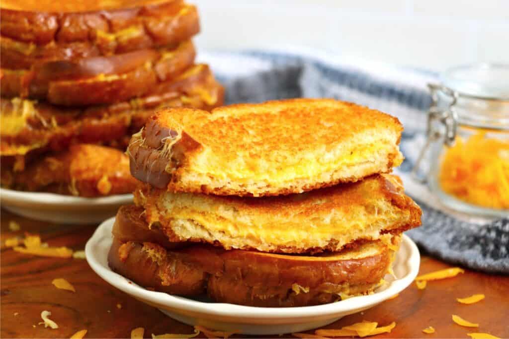 Oven baked grilled cheese sandwich halvs stacked atop one another on plate