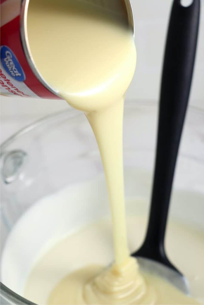 Closeup shot of sweetened condensed milk being poured into mixing bowl with chocolate