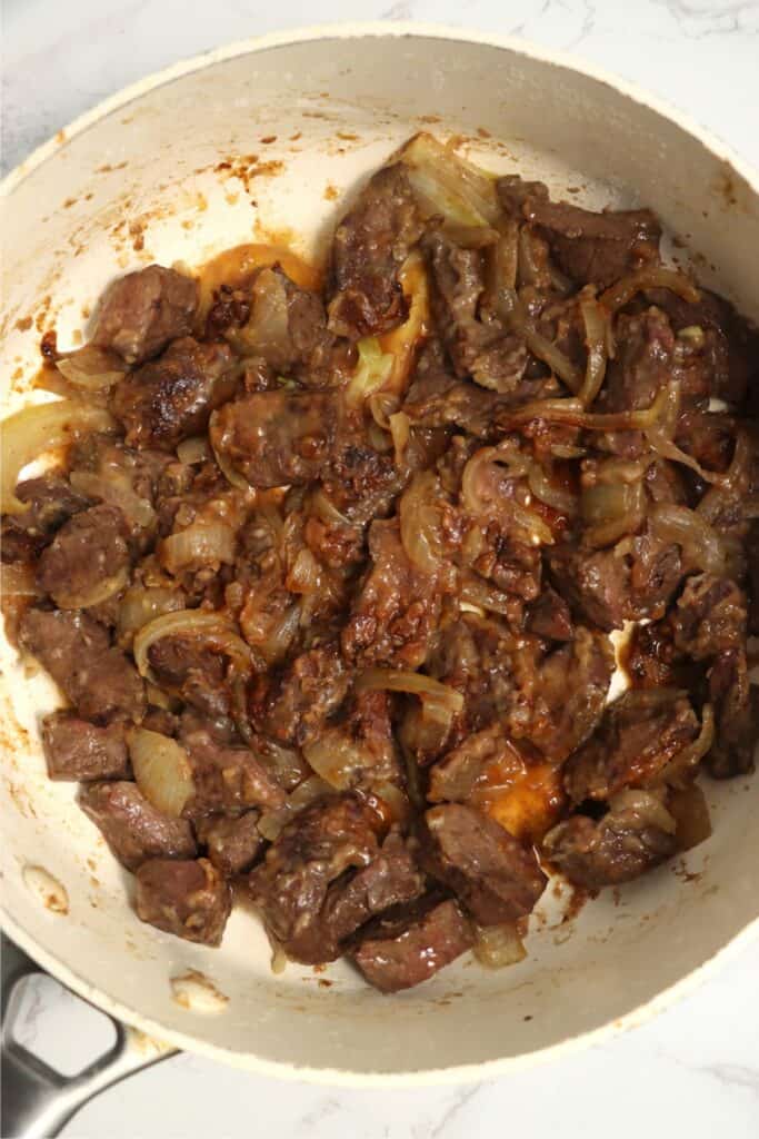 Overhead shot of cooked venison heart and onions in skillet