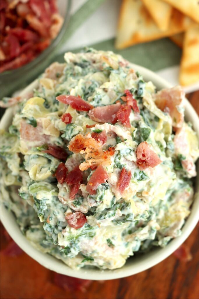 Closeup overhead shot of bowlful of spinach artichoke dip with bacon