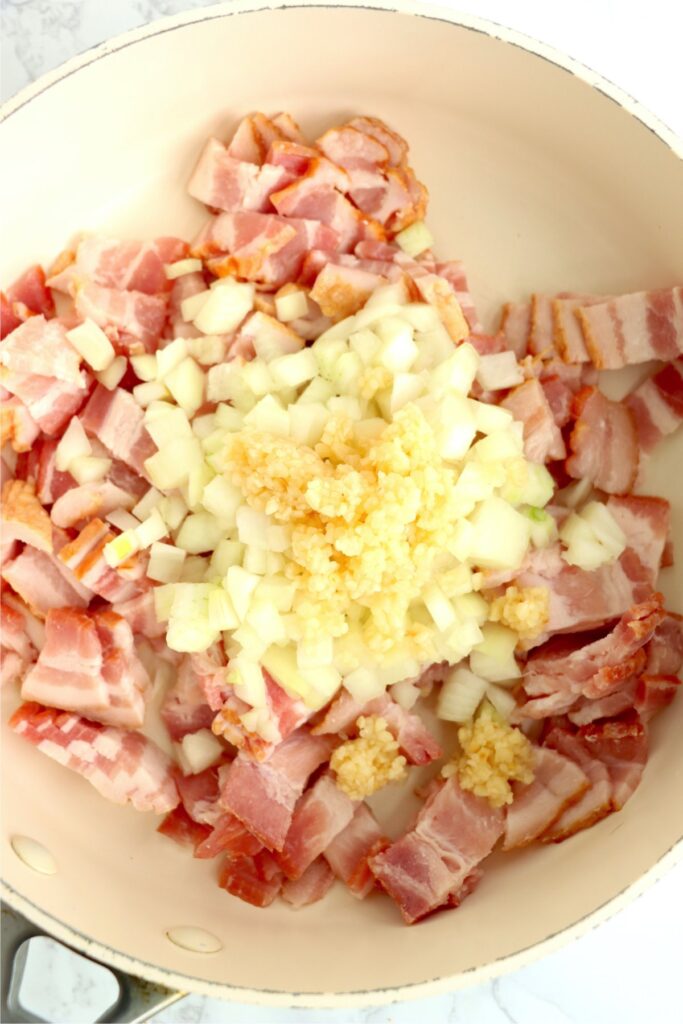 Overhead shot of bacon, onions, and garlic in skillet. 