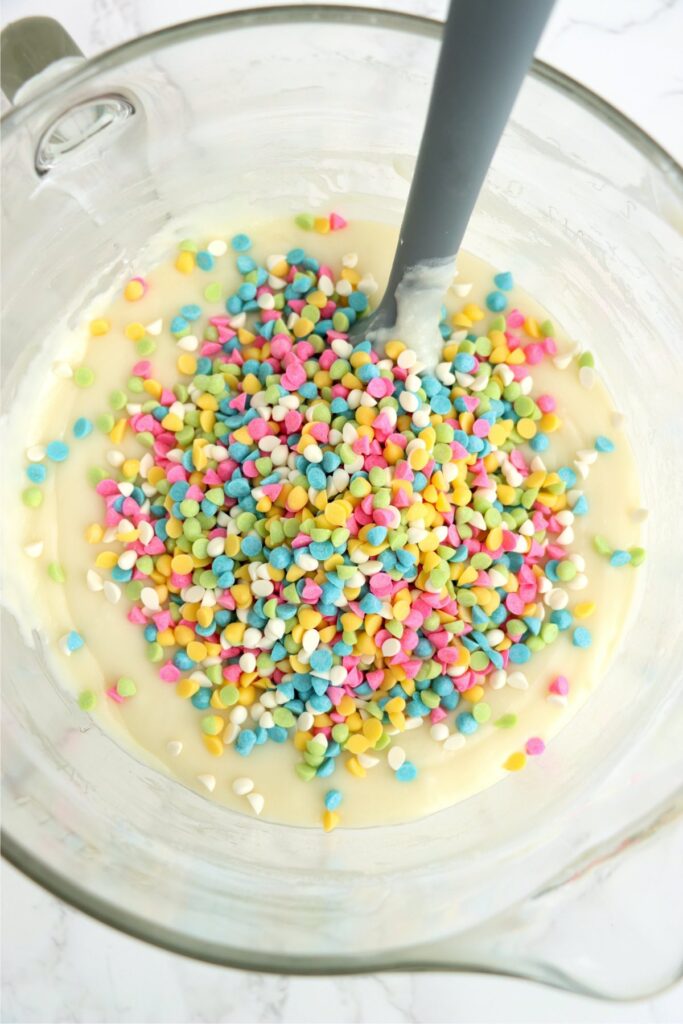 Overhead shot of colord baking chips being mixed into Easter fudge mixture