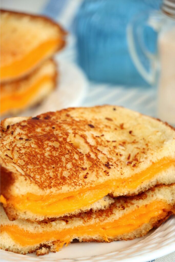 Closeup shot of two halves of garlic grilled cheese sandwich stacked atop one another on plate