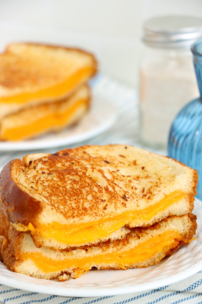 Closeup shot of tow halves of garlic grilled cheese stacked atop one another on plate.