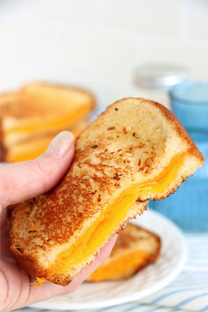 Closeup shot of hand holding half a garlic grilled cheese sandwich