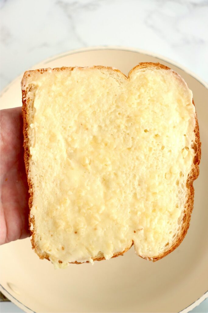 Overhead shot of hand holding bread topped with garlic butter