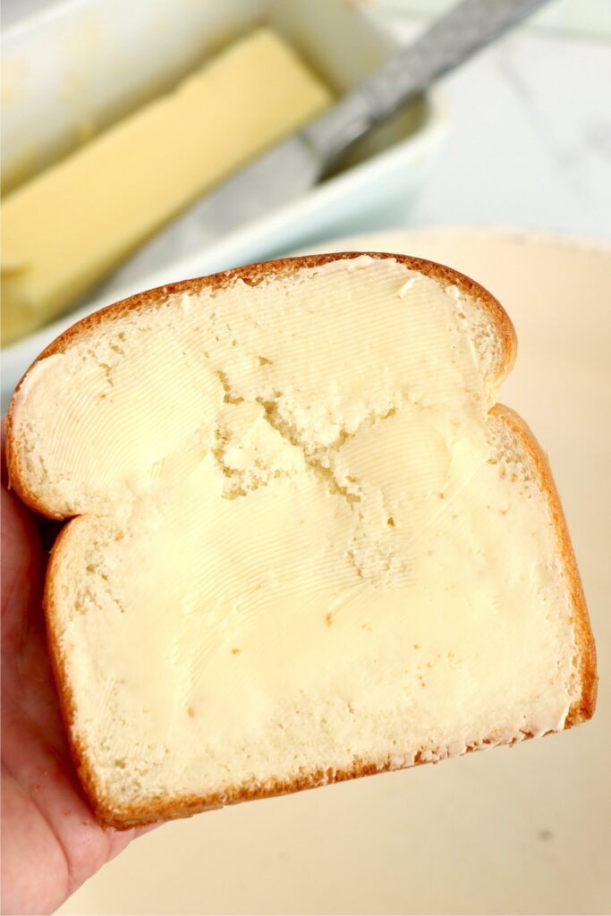 Hand holding a slice of buttered bread