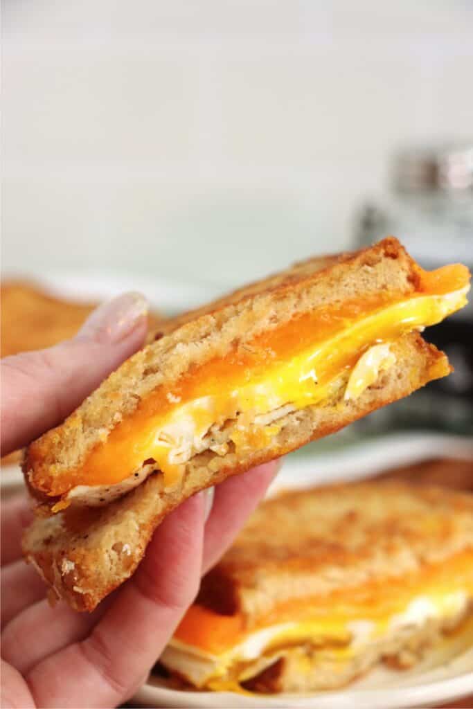 Closeup shot holding half of a grilled cheese and egg sandwich.
