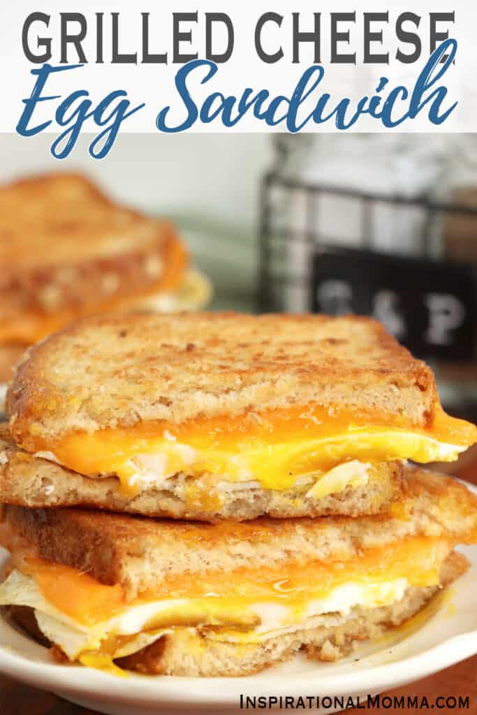 Closeup shot of tow grilled cheese and egg sandwich halves stacked atop one another on plate