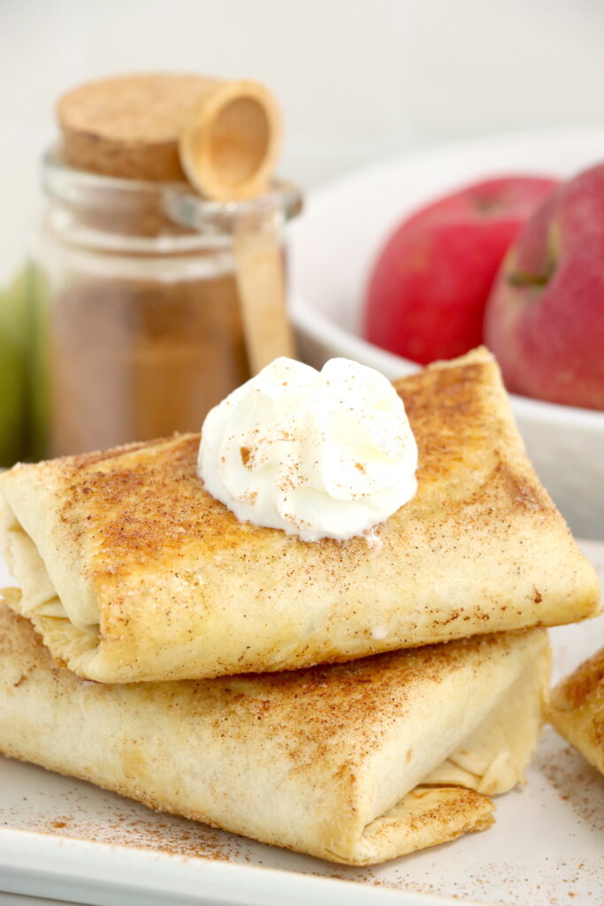 Closeup shot of two homemade apple wraps stacked atop one another on plate. 