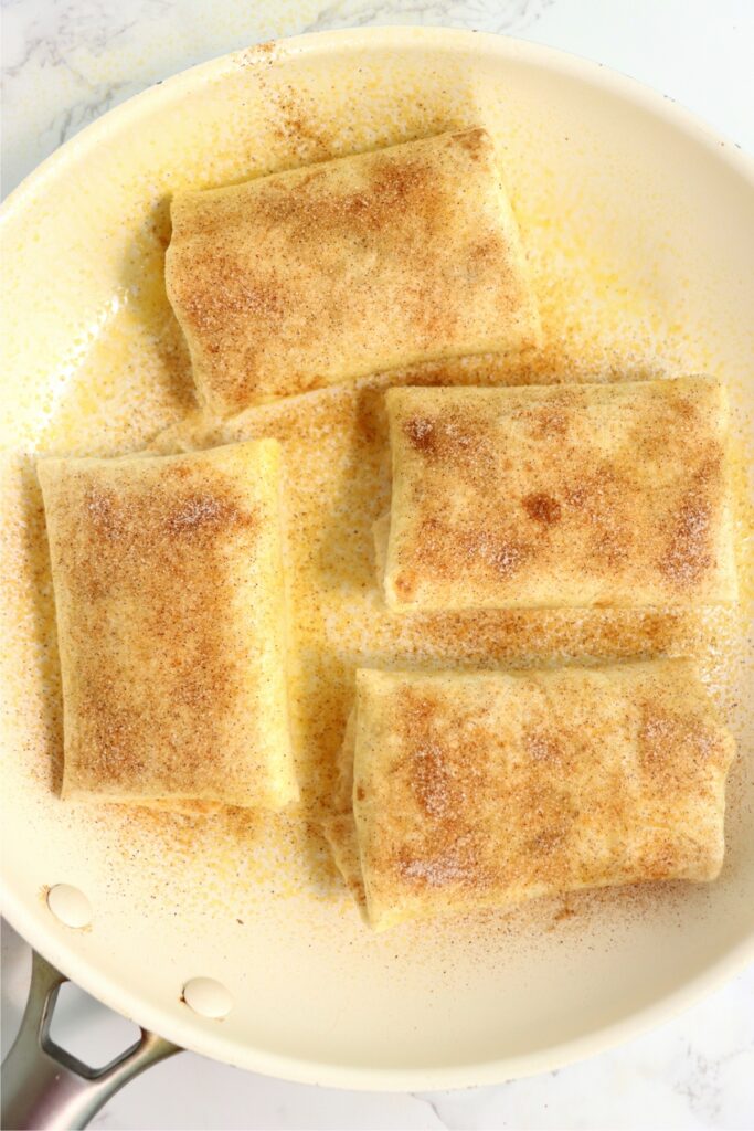 Overhead shot of uncooked homemade apple wraps in skillet