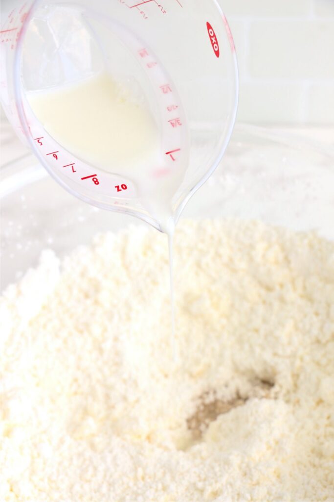 MIlk being poured into bowl of powdered sugar and butter mixture