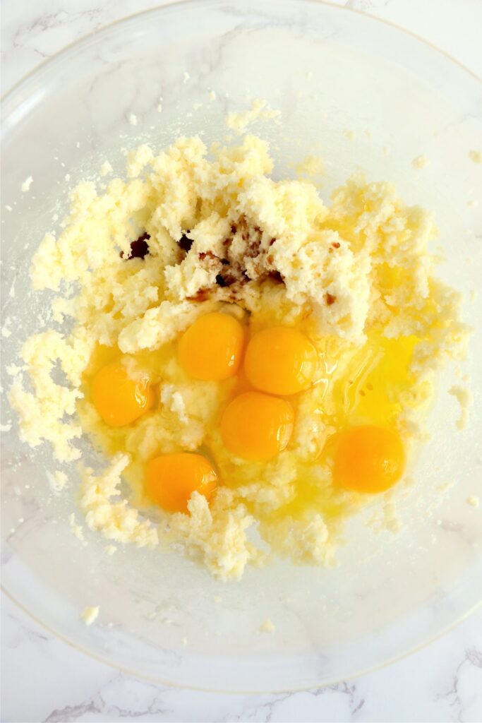 Overhead shot of eggs with creamed butter and sugar in mixing bowl