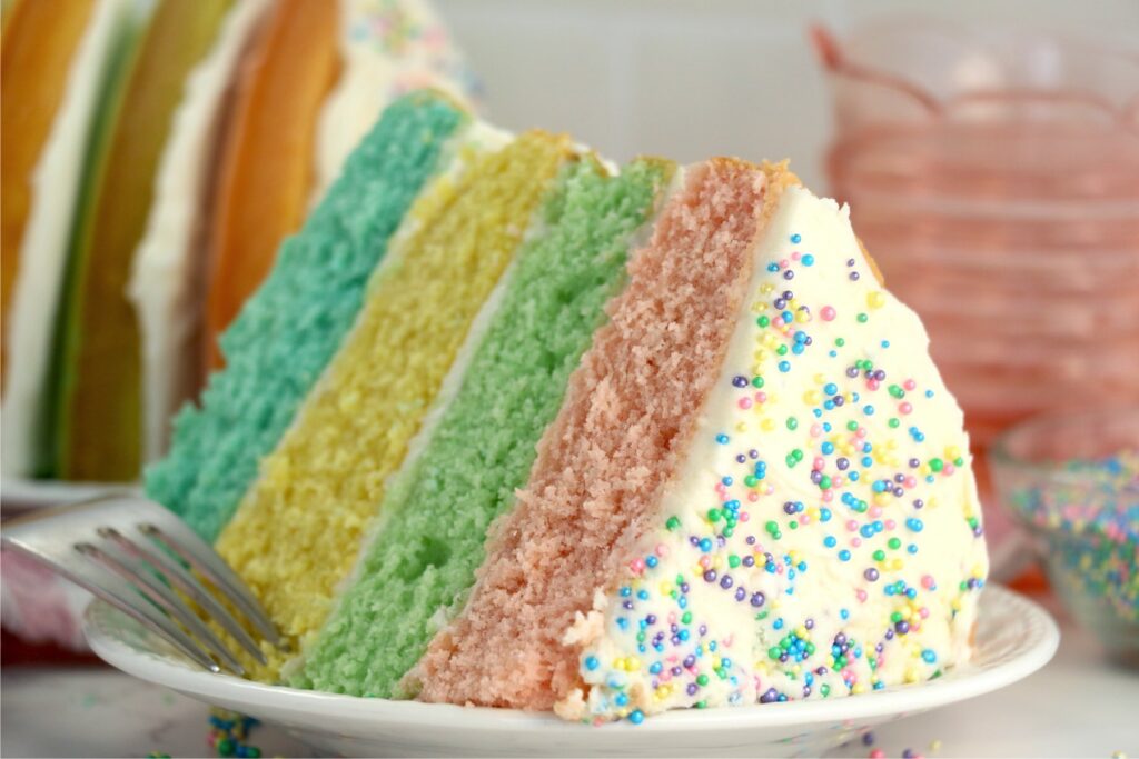 Closeup shot of slice of pastel layer cake with fork on plate