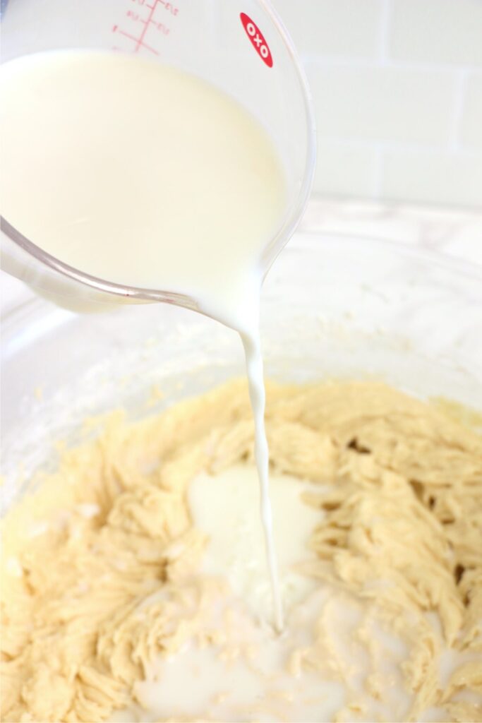 Milk being poured into cake batter in bowl