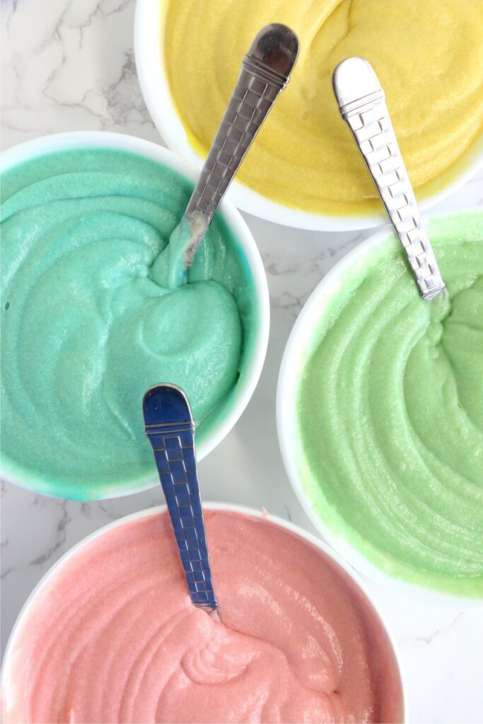 Overhead shot of colored cake batter in bowls