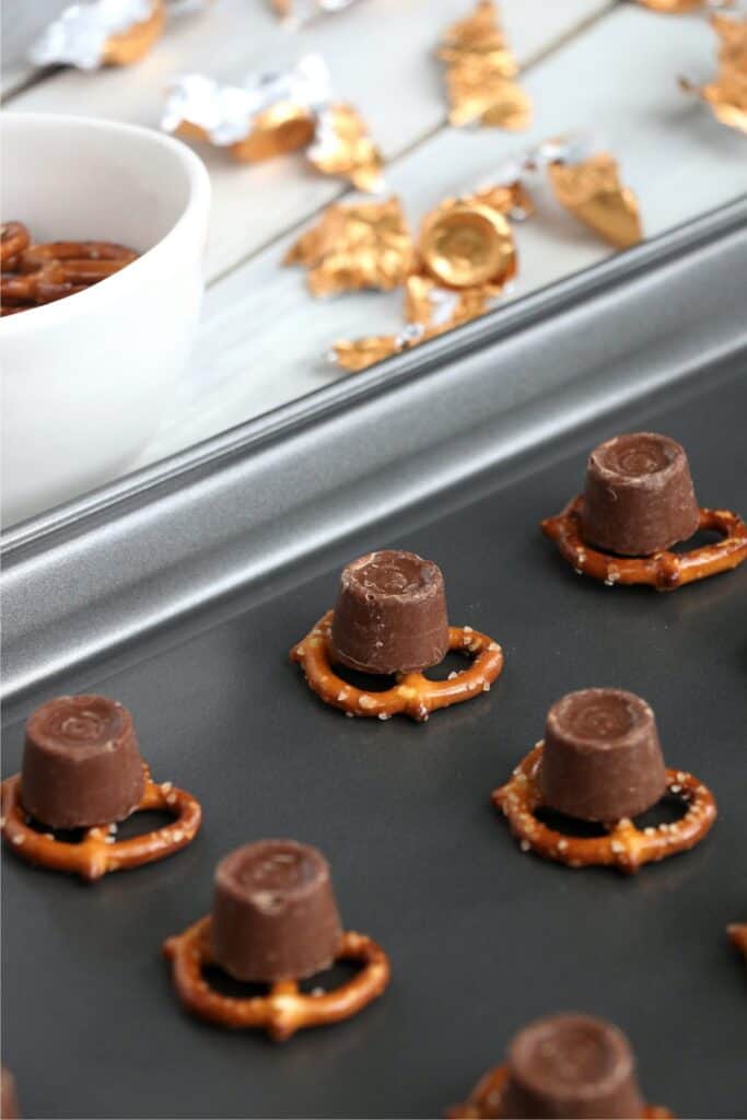Pretzels topped with a Rolo on baking sheet. 