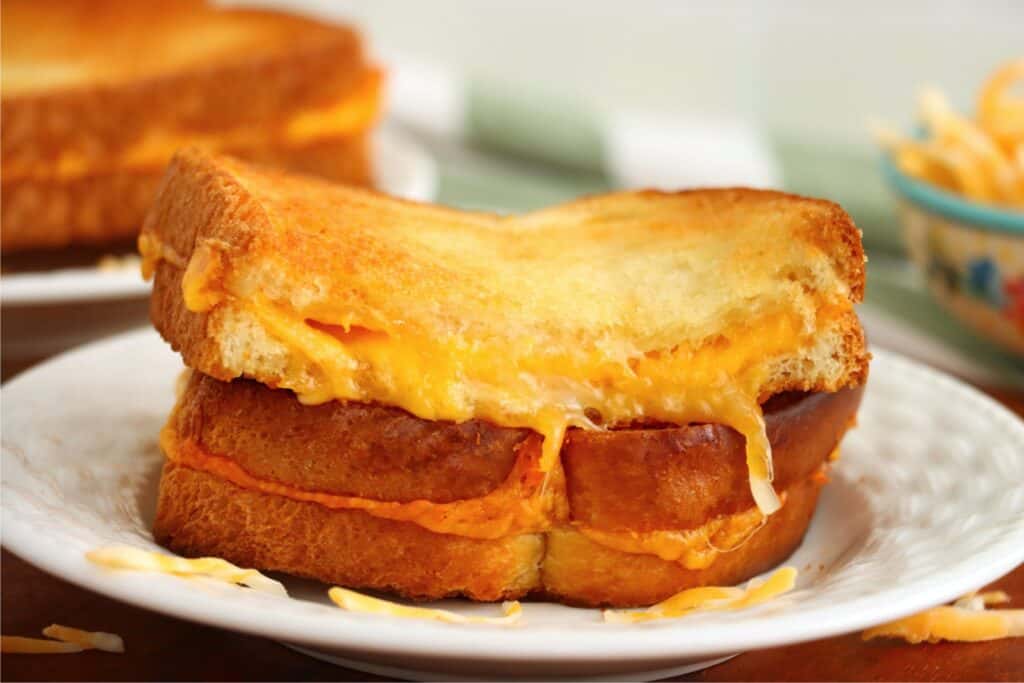 Closeup shot of two toaster oven grilled cheese sandwich halves stacked atop one another on plate
