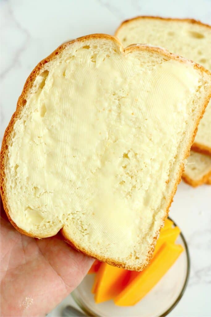 Closeup shot of hand holding piece of buttered bread