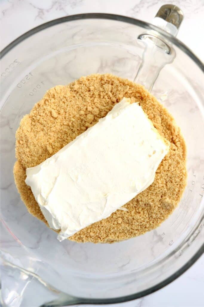 Overhead shot of block of cream cheese in bowlful of Oreo crumbs