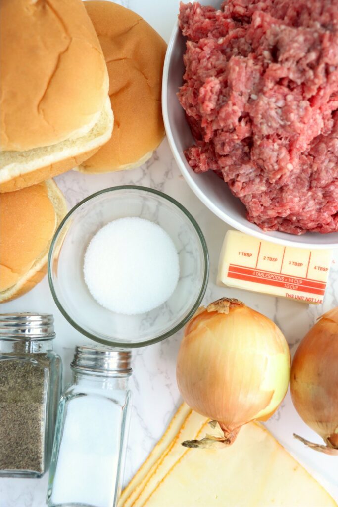 Overhead shot of individual grilled onion cheddar burger ingredients on plate