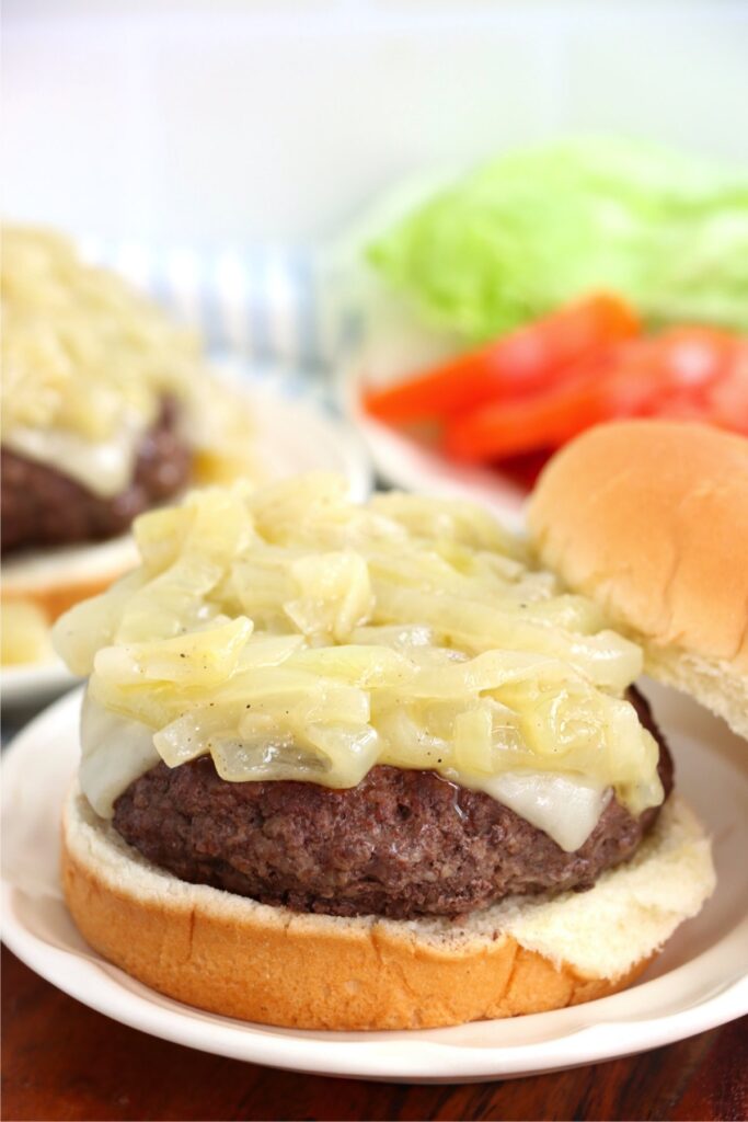 Closeup shot of grilled onion cheddar burger on bun with no top