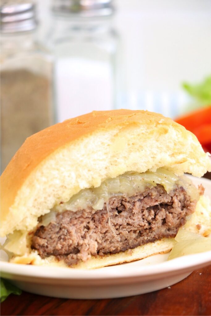 Closeup shot of half a grilled onion cheddar burger on plate