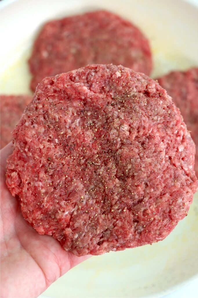 Closeup shot of hand holding a hamburger patty