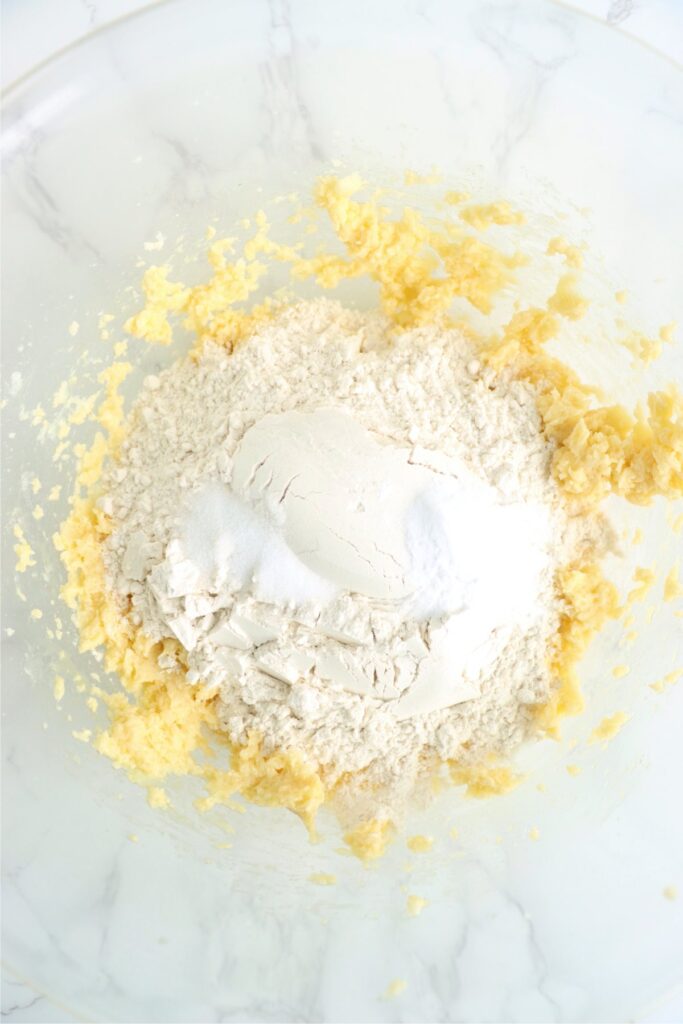 Overhead shot of dry cookie ingredients on top of wet ingredients in mixing bowl