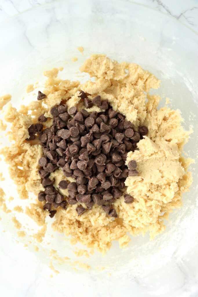 Closeup overhead shot of cookie dough with chocolate chips on top in mixing bowl