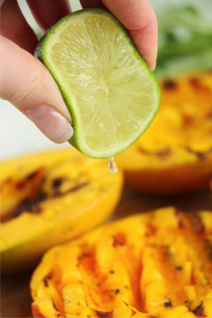 Closeup shot of lime juice being squeezed over grilled mangoes