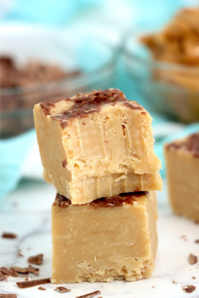  Closeup shot of two no bake peanut butter fudge squares stacked atop one another with bite taken out of top square