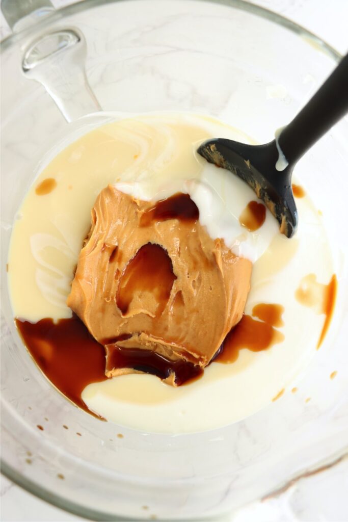 Overhead shot of melted vanilla bark, condensed milk, peanut butter, and vanilla in glass bowl