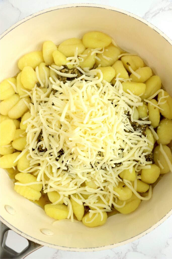 Overhead shot of gnocchi, pesto, and cheese in skillet