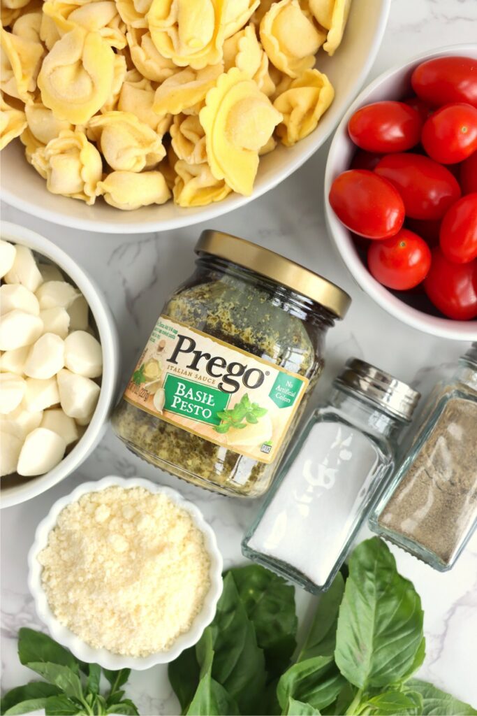 Overhead shot of individual pasta salad ingredients in bowls on table