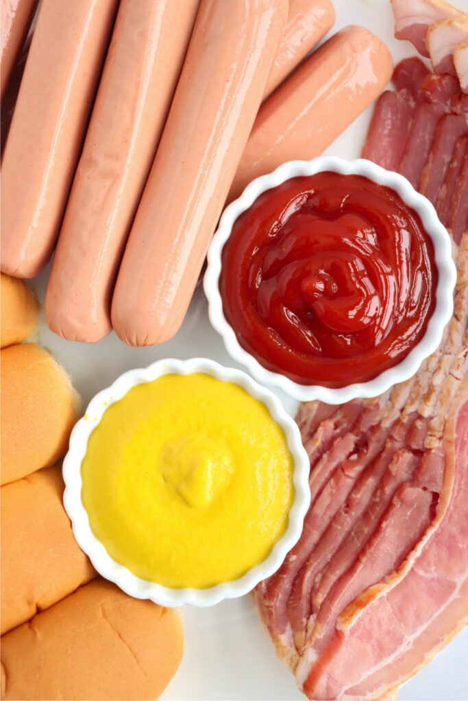 Overhead shot of individual bacon wrapped hot dog ingredients on table