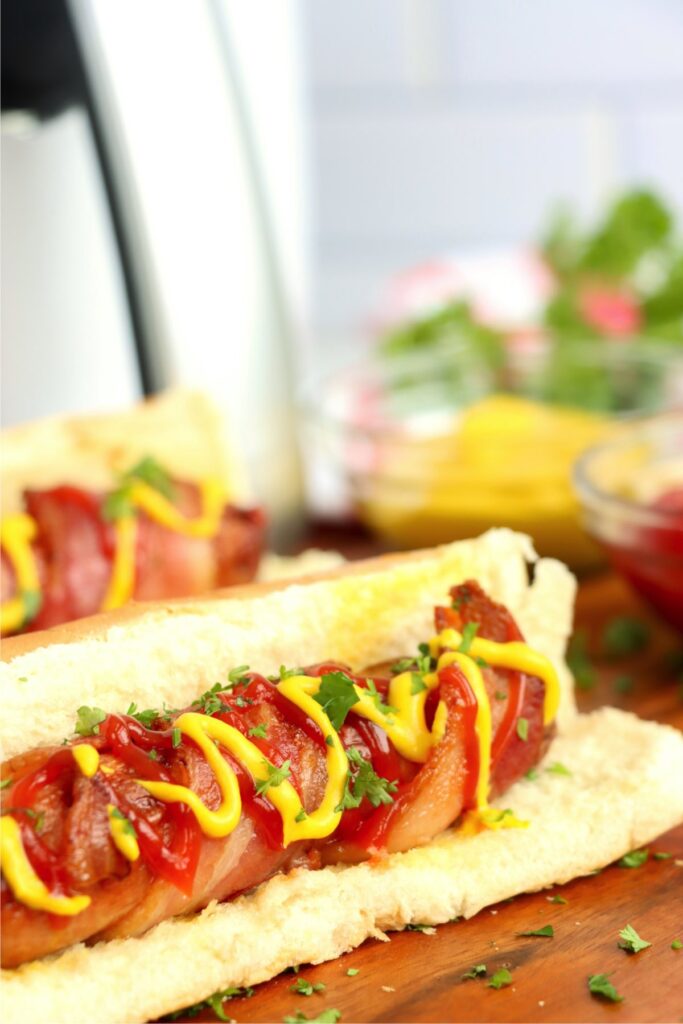 Close up shot of tow air fryer bacon wrapped hot dogs on table. 