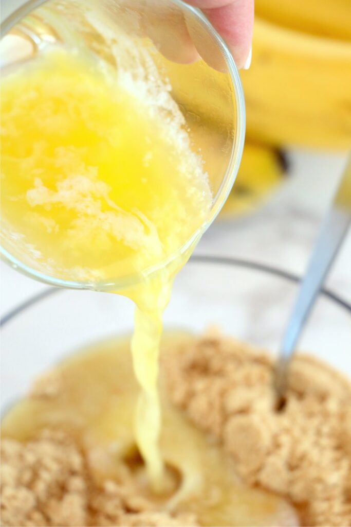 Closeup shot of melted butter being poured into bowlful of vanilla wafer crumbs