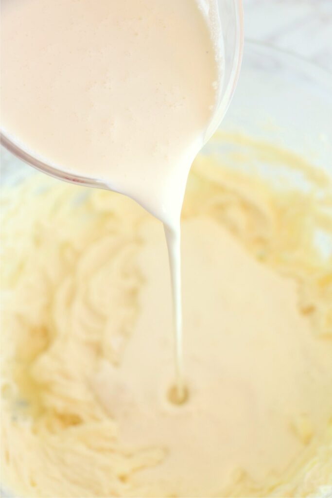 Banana pudding mixture being poured into cream cheese mixture. 