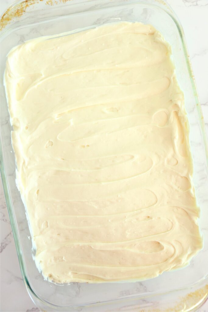 Overhead shot of banana pudding crema cheese mixture spread over crust in baking dish