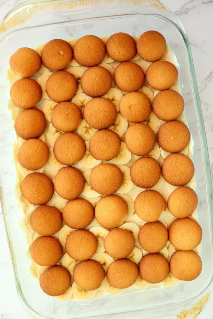 Banana pudding cream cheese mixture topped with bananas and Vanilla wafers in baking dish