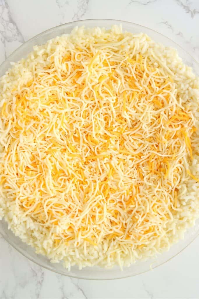 Overhead shot of rice mixture in pie plate topped with cheese.