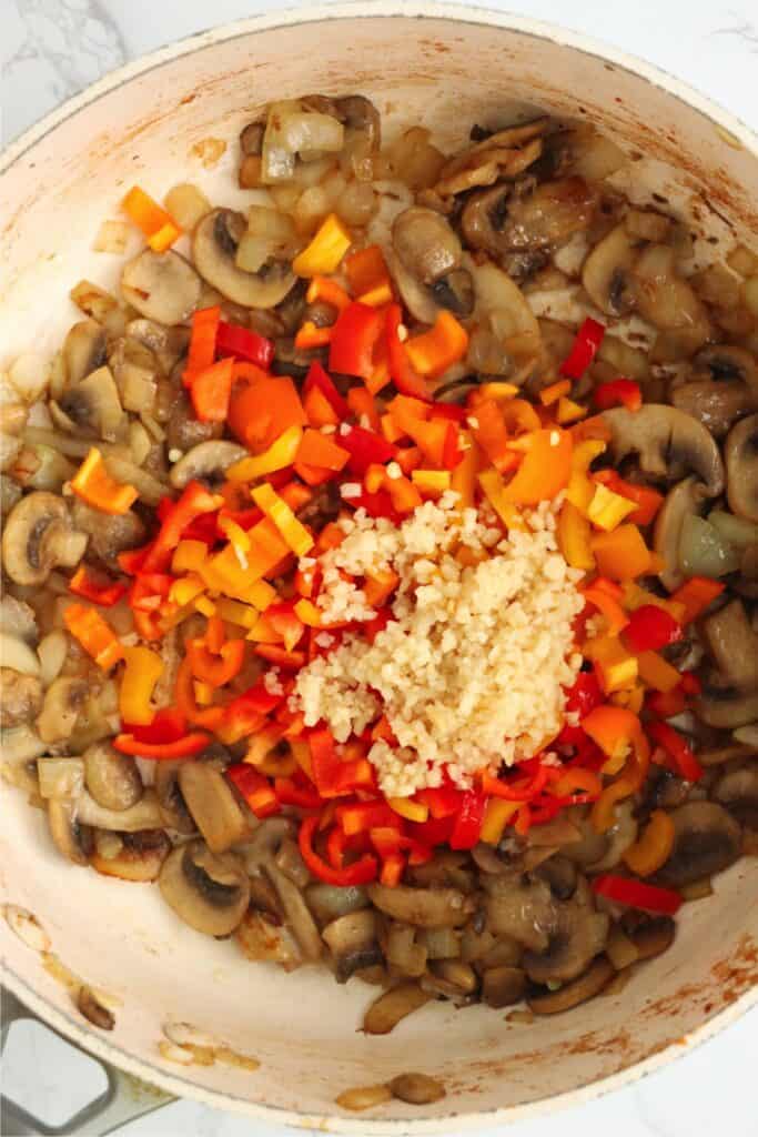 Overhead shot of mushrooms, onions garlic, and bell peppers in pan