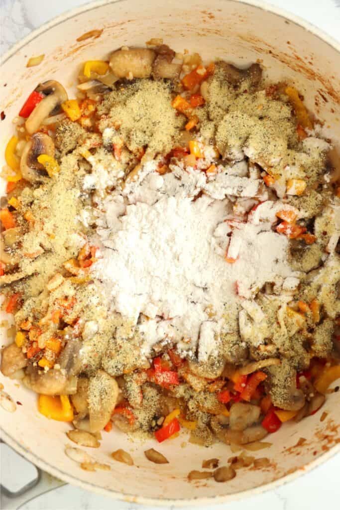 Overhead shot of cooked vegetables topped with Italian seasoning and flour in pan